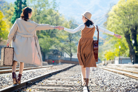 自由旅行者青年女人旅途旅行者青年闺蜜手牵手走在铁轨上背景