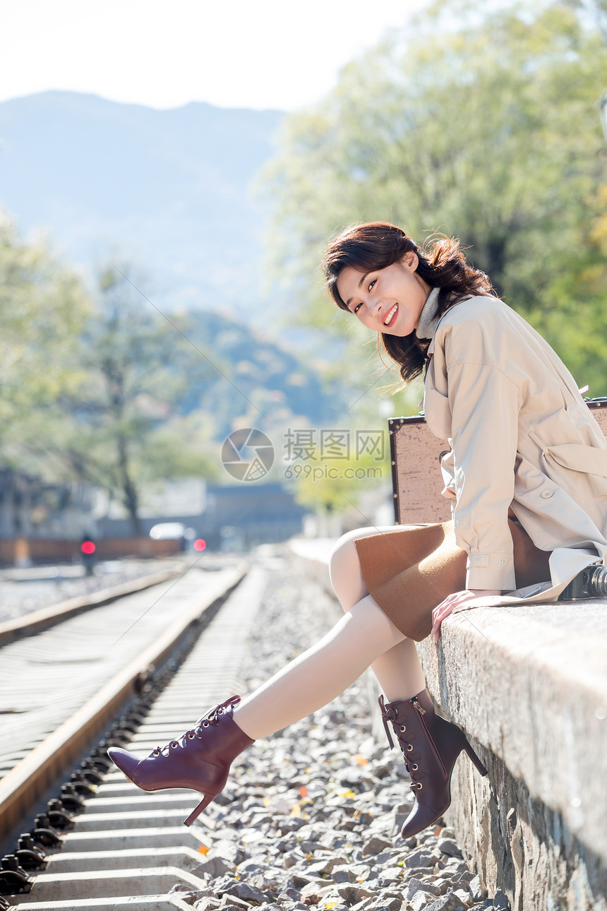 旅途东方人快乐青年女人坐在铁轨旁边图片