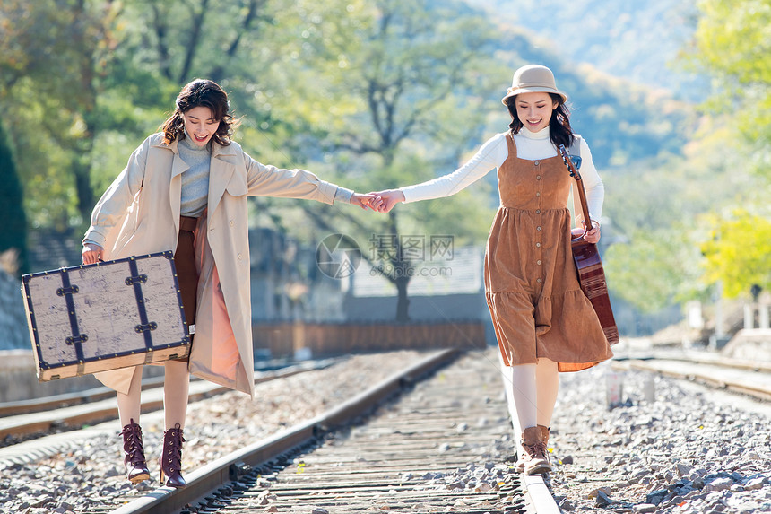 彩色图片度假环境青年闺蜜手牵手走在铁轨上图片