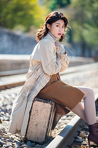大旅行箱方式青年人优雅旅行箱青年女人坐在铁轨上背景
