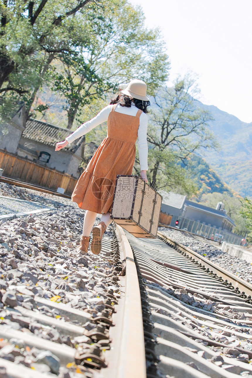 旅途复古背影青年女人在铁轨上行走图片