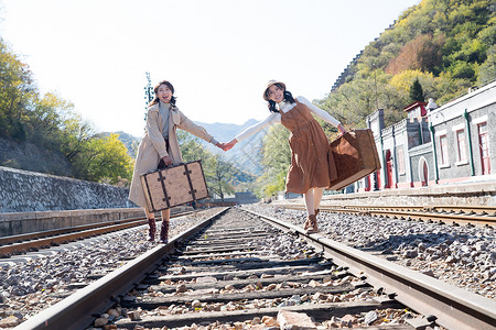 旅途青年闺蜜手牵手走在铁轨上图片