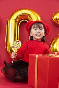 生日愿望新年前夕全身像儿童小女孩过年穿新衣服手拿棒棒糖背景