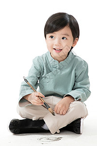 节日东方人春节小男孩盘腿坐着拿毛笔写字高清图片