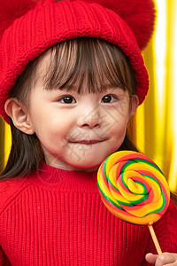新的糖果素材拜年兴奋放松小女孩过年穿新衣服手拿棒棒糖背景