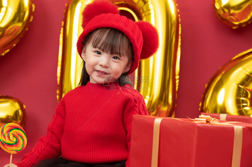 幸福糖果红色背景可爱的小女孩拿着棒棒糖图片