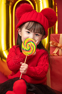 新年新愿望嬉戏的礼品食品小女孩过年穿新衣服手拿棒棒糖背景