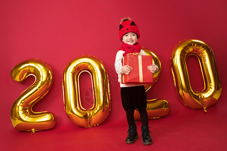 年庆典包装盒彩色图片影棚拍摄可爱的小男孩拿着新年礼物背景