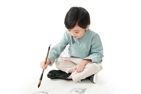 小男孩坐着童年新年前夕欢乐小男孩盘腿坐着拿毛笔写字背景