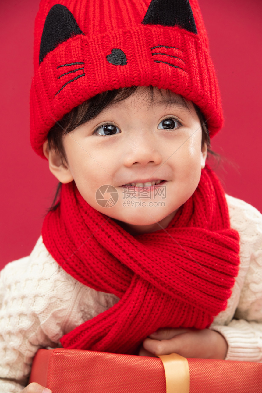 红色背景传统节日童年可爱的小男孩趴在新年礼物上图片