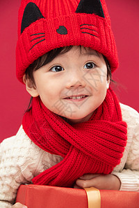 红色背景传统节日童年可爱的小男孩趴在新年礼物上高清图片