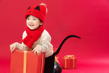 影棚拍摄祝福可爱的小男孩趴在新年礼物上玩耍高清图片