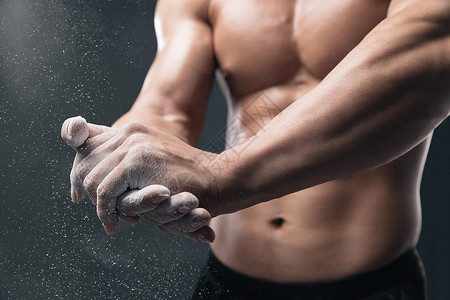 专注塑美健美运动员的手在涂抹防滑粉背景