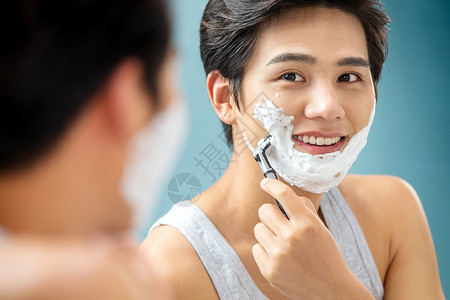 青年男人对着镜子刮胡子高清图片