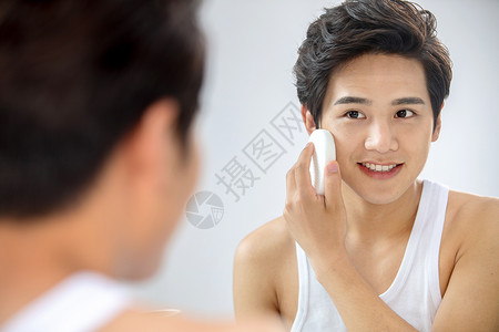 完美欢乐触摸对着镜子用面扑擦脸的年轻男人图片