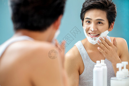青年男人对着镜子抹剃须膏图片