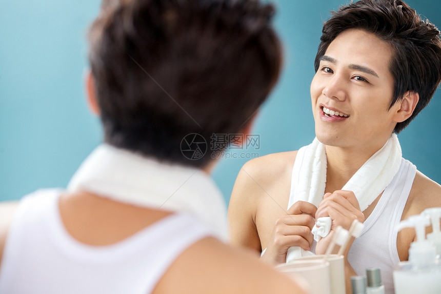 个人护理化妆品表现积极快乐的年轻男人拿着毛巾照镜子图片