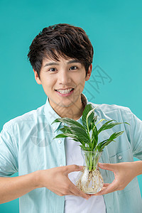 白掌花露齿一笑瓶子玻璃拿着绿色植物的青年男人背景