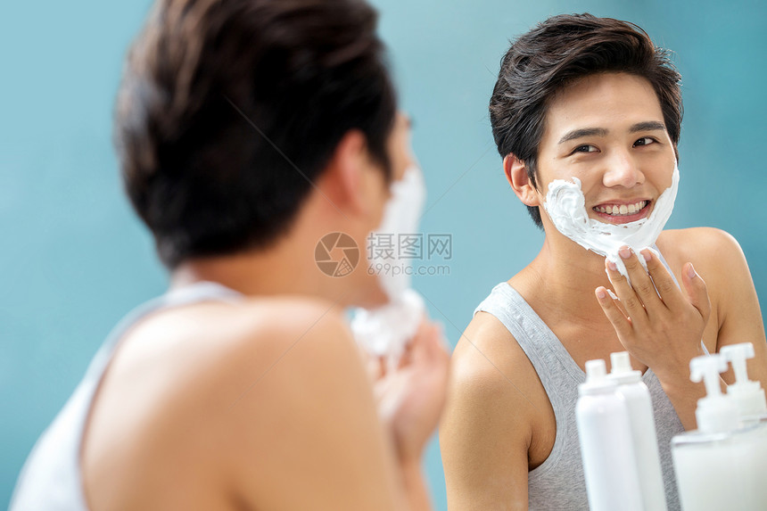 青年男人对着镜子涂抹剃须膏图片
