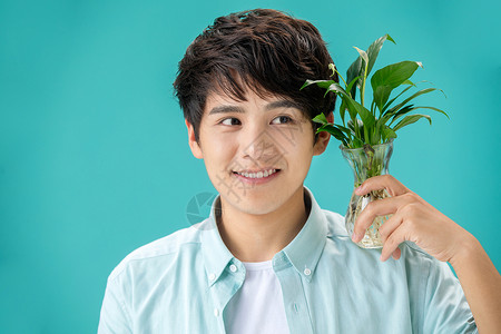 白掌花自然亚洲白掌拿着绿色植物的青年男人背景