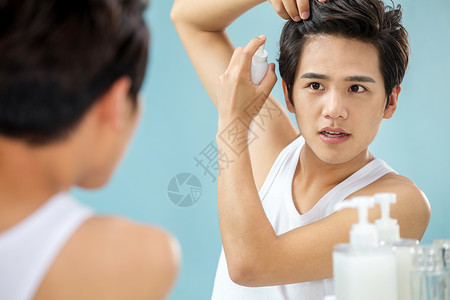 专注塑美准备彩色图片站着照着镜子给头发喷啫喱的年轻男人背景