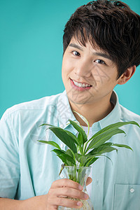 白掌花蓝色背景露齿一笑彩色图片拿着绿色植物的青年男人背景