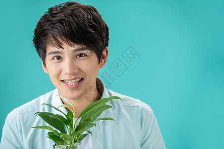 白掌花青年人自然亚洲人拿着绿色植物的青年男人背景