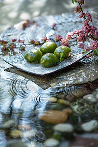 圆形鹅卵石熟的水面上的青团和桃花枝背景图片