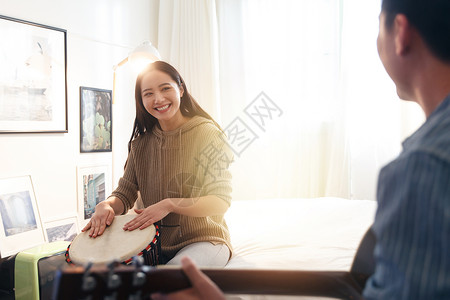 温馨女朋友表现积极快乐情侣在家演奏乐器高清图片