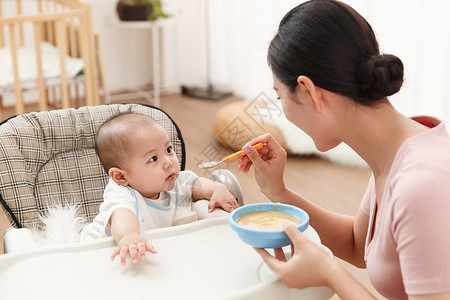 亚洲勺子妈妈喂宝宝吃饭背景