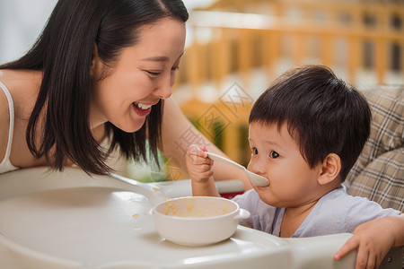 儿童的房间快乐婴儿食品男婴妈妈喂宝宝吃饭背景