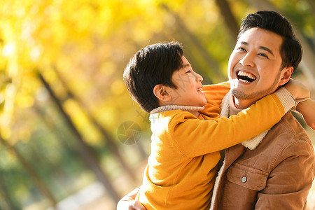 秋天公园里父亲和儿子在户外玩耍高清图片