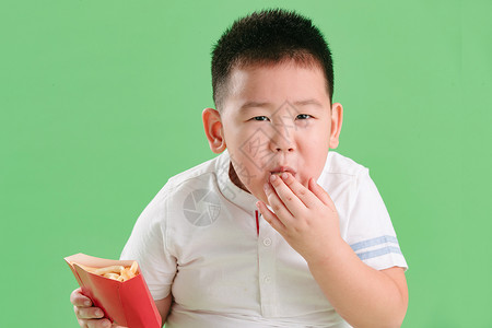 饥饿的脸诱惑影棚拍摄亚洲可爱的小男孩吃薯条背景