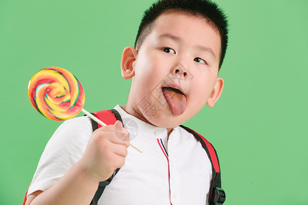 东方人人有趣的可爱的小男孩拿着棒棒糖图片