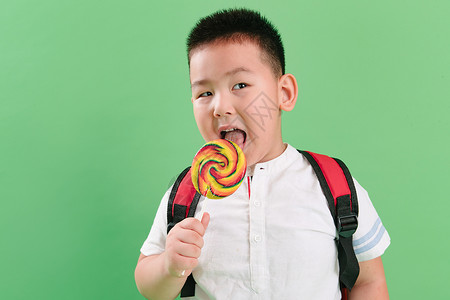 孩子吃甜食休闲装食品纯净可爱的小男孩拿着棒棒糖背景