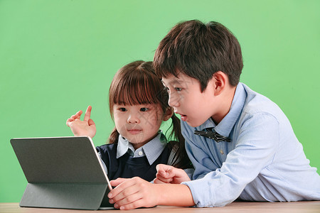 绿色背景天真儿童两个小伙伴使用平板电脑图片