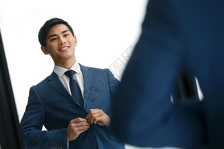不看镜头活力亚洲商务青年男人在镜子前穿衣服背景图片