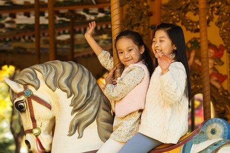 游乐场两个小女孩在玩旋转木马图片