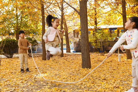 黄色绳子圆环秋天树林中周末活动男孩女孩在户外玩耍背景