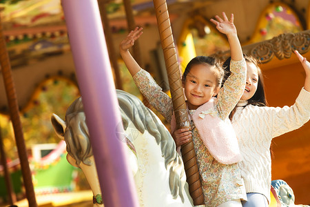 户外幸福活动两个小女孩在玩旋转木马图片