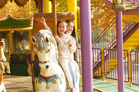 仅女孩无忧无虑公园两个小女孩在玩旋转木马图片