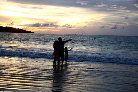 印度景观自然美非都市风光度假巴厘岛海滩上的家庭剪影背景