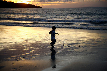 跑步金色人旅游胜地巴厘岛海滩上的小孩剪影背景