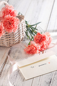 纯英文母亲节桌上的康乃馨花和信封贺卡背景