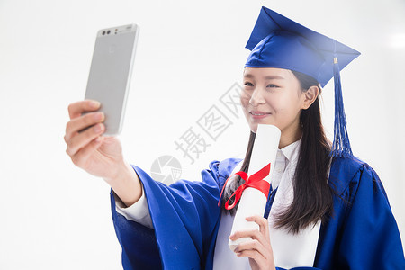 穿学士服的大学生用手机拍照图片