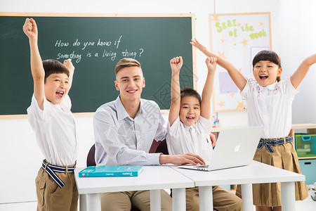 电脑教师教师和小学生在教室里背景