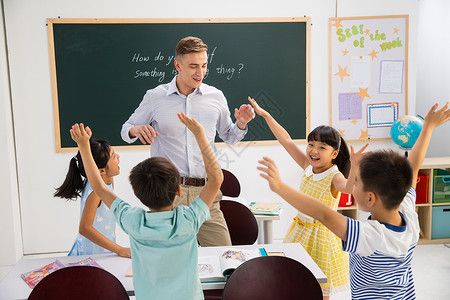 国际义工教师课桌教育未成年学生教师和小学生在教室里背景