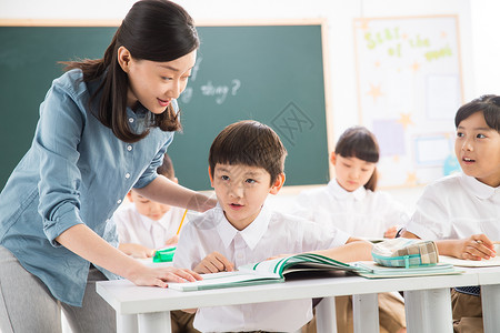 摄影相伴小学女生老师和小学生们在教室里图片