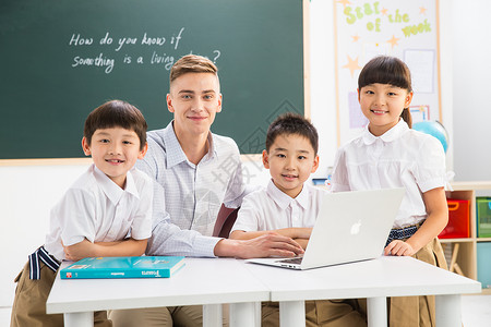 相伴电脑户内教师和小学生在教室里背景图片