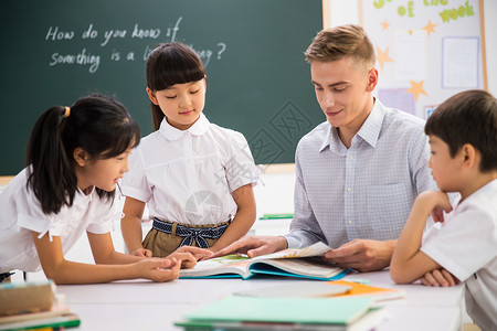 外教孩子外教老师和小学生在教室里背景